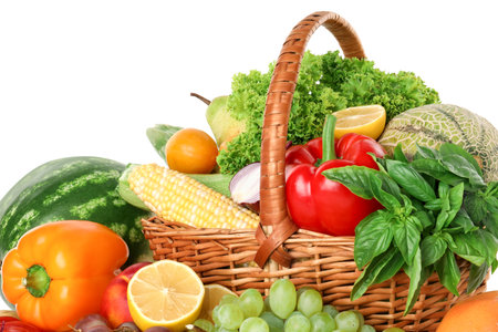 Different fresh fruits and vegetables in wicker basket isolated on whiteの写真素材