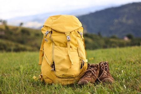 Backpack and trekking shoes on green grass outdoorsの写真素材