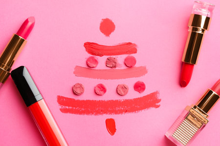 Christmas tree drawn with lipsticks on pink background, flat layの写真素材