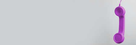 Purple corded telephone handset on gray background. Banner design with space for textの写真素材