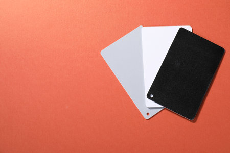 White balance calibration cards on red background, top view. Space for text