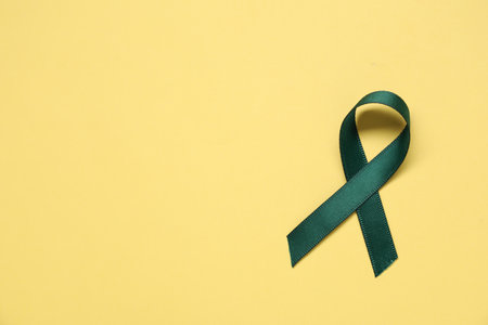Green awareness ribbon on yellow background, top view. Space for textの写真素材