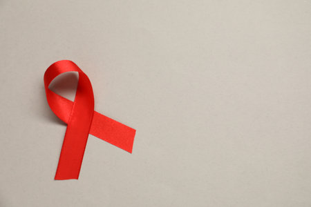 Red awareness ribbon on gray background, top view. Space for textの写真素材