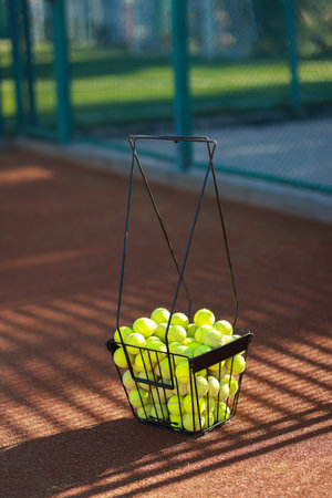 Many tennis balls in metal basket on courtの写真素材