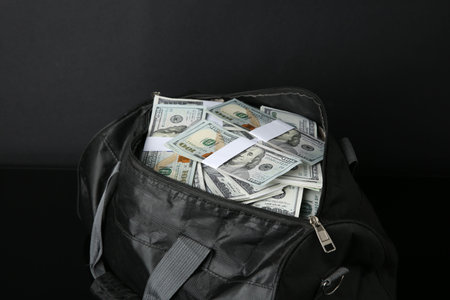 Dollar banknotes in bag on black table, closeup