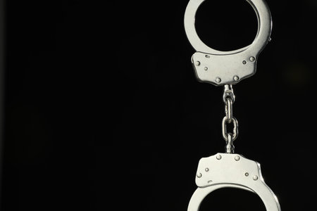 Metal chain handcuffs on black background, closeup. Space for textの写真素材