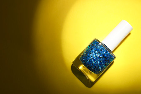 Nail polish in bottle on yellow background, top view. Space for textの写真素材