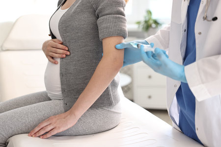 Doctor giving injection to pregnant woman at hospital, closeupの写真素材