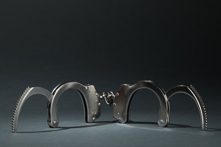 Metal chain handcuffs on gray background, closeup. Space for text