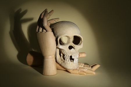 Wooden mannequin hands holding human skull on beige backgroundの写真素材