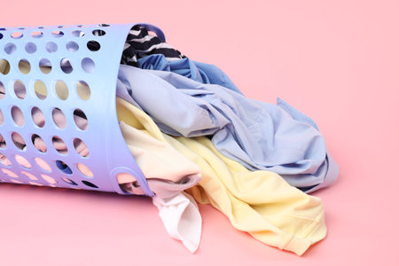 Overturned laundry basket full of clothes on pink backgroundの写真素材