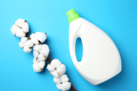 Bottle of laundry detergent and cotton flowers on blue background, flat layの写真素材