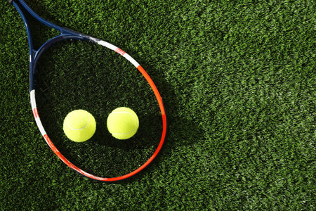 Tennis racket and balls on green artificial grass, flat lay. Space for textの写真素材