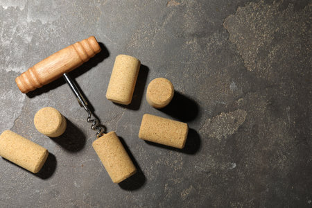Corkscrew and corks on gray table, flat lay. Space for text