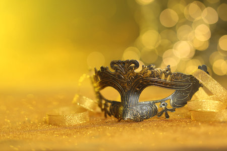 Beautiful carnival mask on golden shiny surface, closeup. Space for textの写真素材