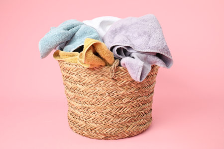 Wicker basket full of laundry on pink backgroundの写真素材