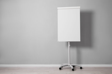 Flip chart near gray wall indoors. Mockup for designの写真素材