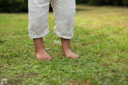 Little child standing barefoot on green grass outdoors, closeup. Enjoying natureの写真素材