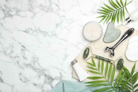 Flat lay composition with face rollers and gua sha tool on white marble background, space for textの写真素材