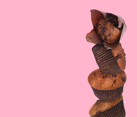 Stacked tasty chocolate chip muffins on pink background. Space for textの写真素材