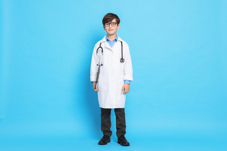 Boy with stethoscope pretending to be doctor on light blue background. Dreaming of future professionの写真素材