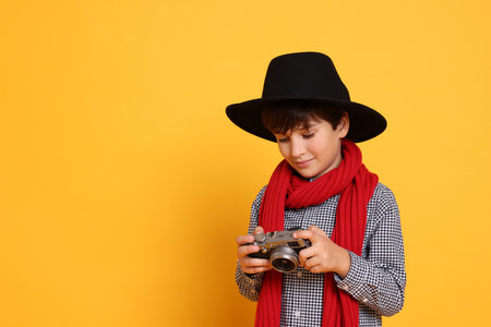 Boy with camera pretending to be photographer on orange background, space for text. Dreaming of future professionの写真素材