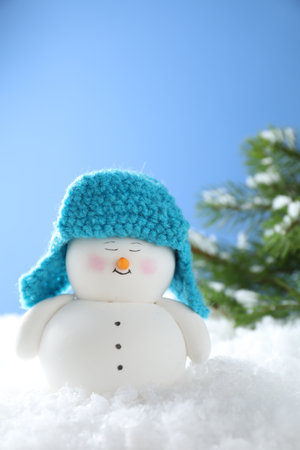Cute decorative snowman on artificial snow against light blue backgroundの写真素材