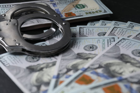 Corruption. Handcuffs and dollar banknotes on black table, closeupの写真素材