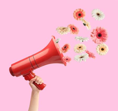 Gerbera flowers flying out of red loudspeaker in woman's hand on pink background, closeupの写真素材