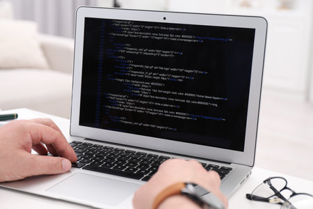 Programmer working with laptop at white desk in office, closeupの写真素材