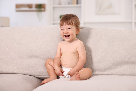 Little child in diaper on sofa at homeの写真素材