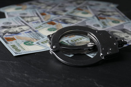 Corruption. Handcuffs and dollar banknotes on black table, closeupの写真素材
