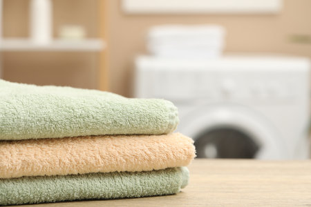 Stack of terry towels on wooden table in laundry room, closeup. Space for textの写真素材