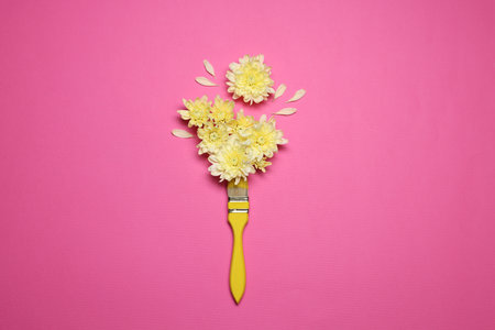 Beautiful flowers and paint brush on pink background, top view