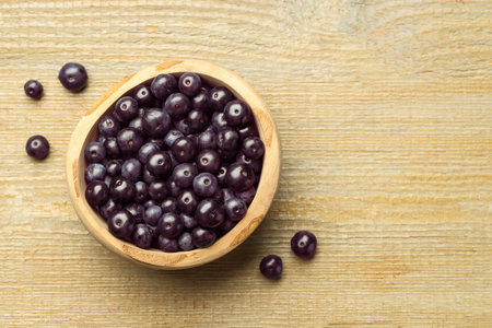 Ripe acai berries in bowl on wooden table, top view. Space for textの写真素材