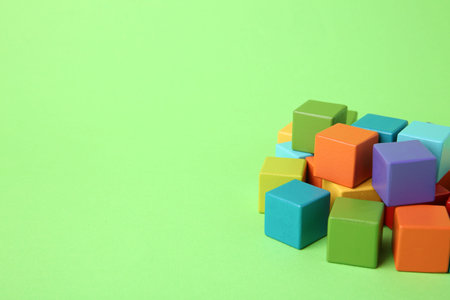 Many wooden colorful cubes on green background, space for textの写真素材