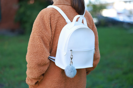 Woman with faux fur keychain on her backpack outdoors, closeup