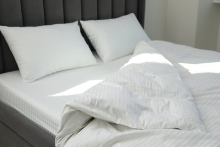 Comfortable bed with clean lines and pillows indoorsの写真素材