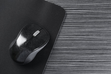 Computer mouse with mousepad on black wooden table, top view. Space for text