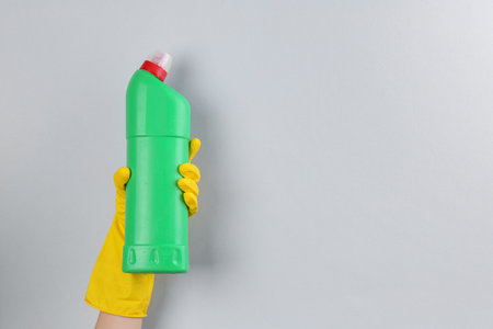 Woman holding toilet cleaner in bottle on light background, closeup. Space for textの写真素材