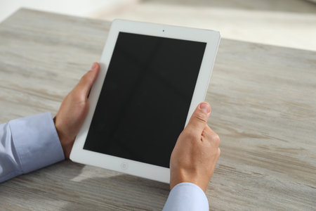 Businessman using tablet at wooden table, closeup. Modern technologyの写真素材