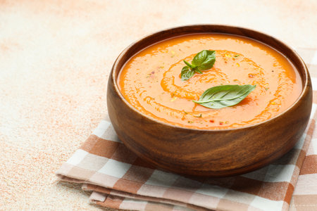 Delicious sweet potato soup with spices and basil in bowl on beige textured table, closeupの写真素材