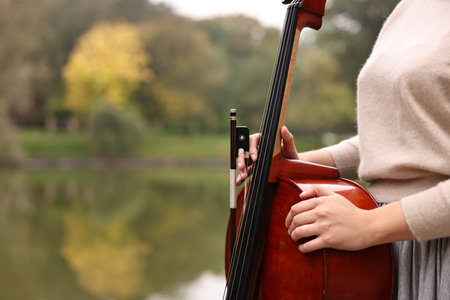 Young woman with cello in park, closeup. Space for textの写真素材