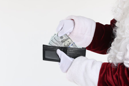 Santa Claus taking dollar banknotes out of wallet on white background, closeup. Space for textの写真素材