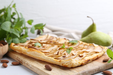 Delicious puff pastry tart with pears, almond and mint on light table, closeupの写真素材