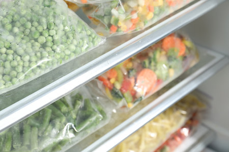 Plastic bags with different frozen vegetables in refrigerator, closeupの写真素材
