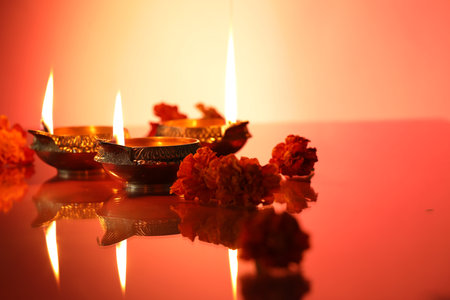 Diwali celebration. Diya lamps and beautiful flowers on color background, closeup. Space for textの写真素材
