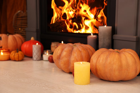 Pumpkins and burning candles near fireplace indoors. Halloween decorationの写真素材