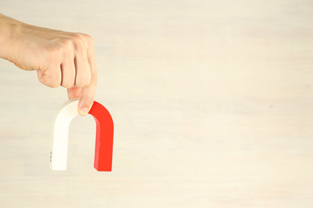 Person holding horseshoe magnet against light background, closeup. Space for textの写真素材