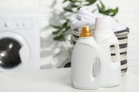 Detergents and basket with towels on white table in bathroom, space for textの写真素材